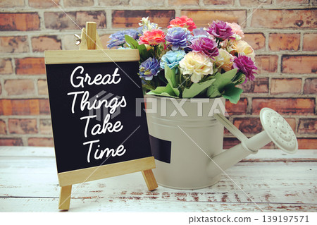 Great Things Take Time text on black wooden easel and vase with flowers bouquet on brick wall background 139197571