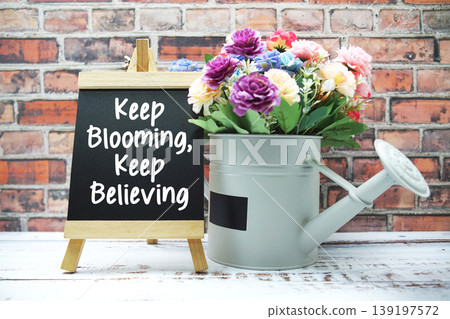 Keep Blooming, Keep Believing text on black wooden easel and vase with flowers bouquet on brick wall background Keep Blooming, Keep Believing text on black wooden easel and vase with flowers bouquet on brick wall background 139197572