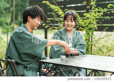 一對穿著浴衣的夫婦在傳統日式旅館的花園露臺上喝清酒 一對穿著浴衣的夫婦在傳統日式旅館的花園露臺上喝清酒 139197673