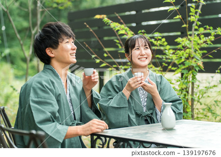 一對情侶在旅途中一邊喝清酒一邊享受森林浴 一對情侶在旅途中一邊喝清酒一邊享受森林浴 139197676
