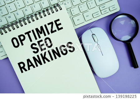 Notepad with the text "Optimize SEO Rankings" and white keyboard, wireless mouse and magnifying glass on purple background 139198225