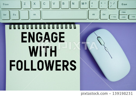 Notepad with the text "Engage With Followers" and white keyboard and wireless mouse on purple background 139198231