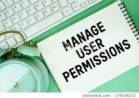 Notepad with the text "Manage User Permissions" and white keyboard and alarm clock on green background 139198252