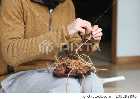 A man undoing the strings on dried persimmons A man undoing the strings on dried persimmons 139198896