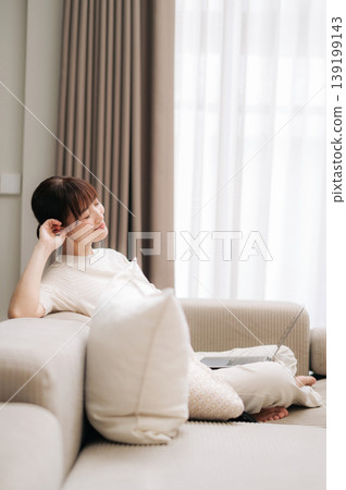 Beautiful peaceful asian woman resting on comfortable living room sofa after remote business work and home study 139199143