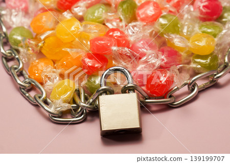 Candies secured with chain and padlock symbolizing restriction Candies secured with chain and padlock symbolizing restriction 139199707