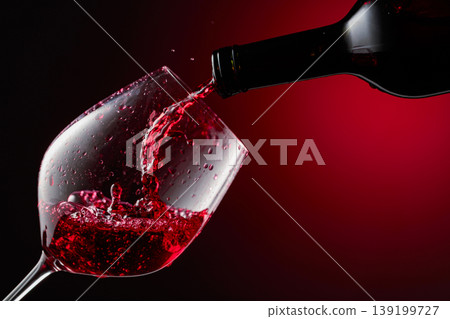 Red wine is poured from a bottle into a glass. Red wine is poured from a bottle into a glass. 139199727