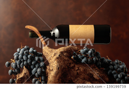 Unopened bottle of red wine, blue grapes, and old snag. Unopened bottle of red wine, blue grapes, and old snag. 139199739