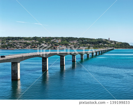 An August photograph taken from above, showing the Kouri Bridge and Kouri Island stretching across the emerald green sea in midsummer. An August photograph taken from above, showing the Kouri Bridge and Kouri Island stretching across the emerald green sea in midsummer. 139199833