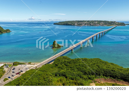 A photograph taken from the midsummer sky, showing the Kouri Bridge stretching across the emerald blue sea and Kouri Island. A photograph taken from the midsummer sky, showing the Kouri Bridge stretching across the emerald blue sea and Kouri Island. 139200020