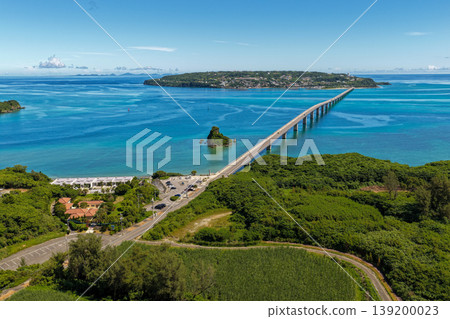 A photograph taken from the midsummer sky, showing the Kouri Bridge stretching across the emerald blue sea and Kouri Island. A photograph taken from the midsummer sky, showing the Kouri Bridge stretching across the emerald blue sea and Kouri Island. 139200023
