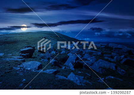 rocks and rolling hills in mountain landscape in summer at night. full moon over scenery with green grass on alpine meadow under dark sky with clouds. mysterious recreation tourism and wanderlust rocks and rolling hills in mountain landscape in summer at night. full moon over scenery with green grass on alpine meadow under dark sky with clouds. mysterious recreation tourism and wanderlust 139200287
