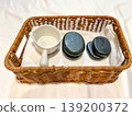 Hot stone massage set in woven basket with smooth basalt stones, towel, and ceramic bowl. Spa wellness concept for relaxation, therapy treatment, body care routine, and luxury beauty service setting 139200372