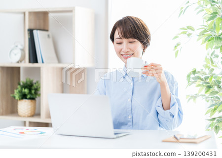 A middle-aged woman who teleworks in the living room. A middle-aged woman who teleworks in the living room. 139200431