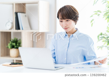 A middle-aged woman who teleworks in the living room. A middle-aged woman who teleworks in the living room. 139200462