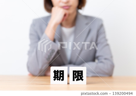 A middle-aged woman in a suit is troubled by a deadline block. A middle-aged woman in a suit is troubled by a deadline block. 139200494