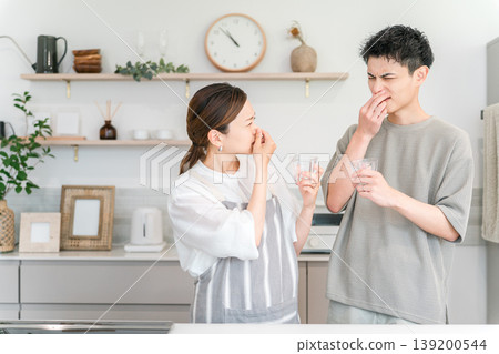 A young Asian couple having trouble with bad-tasting tap water in the kitchen A young Asian couple having trouble with bad-tasting tap water in the kitchen 139200544