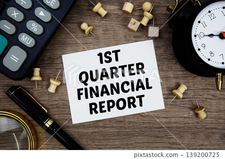 1st Quarter Financial Report text written on notepad with pen, alarm clock, magnifying glass and calculator on wooden background 139200725