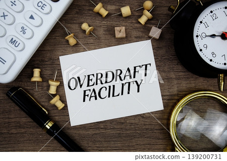Overdraft Facility text written on notepad with pen, alarm clock, magnifying glass and calculator on wooden background Overdraft Facility text written on notepad with pen, alarm clock, magnifying glass and calculator on wooden background 139200731