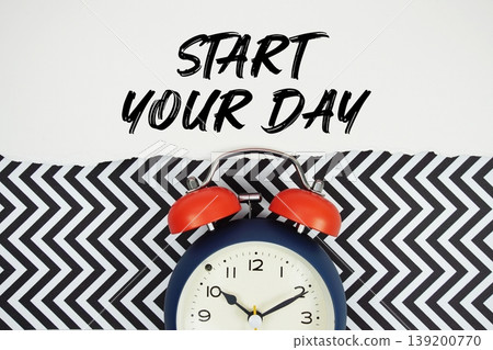 Start Your Day text written on paper rip with alarm clock flat lay on black chevron background 139200770