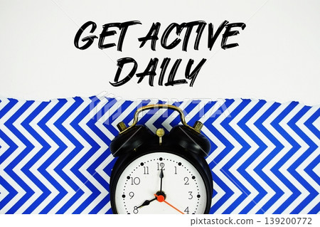 Get Active Daily text written on paper rip with alarm clock flat lay on blue chevron background Get Active Daily text written on paper rip with alarm clock flat lay on blue chevron background 139200772