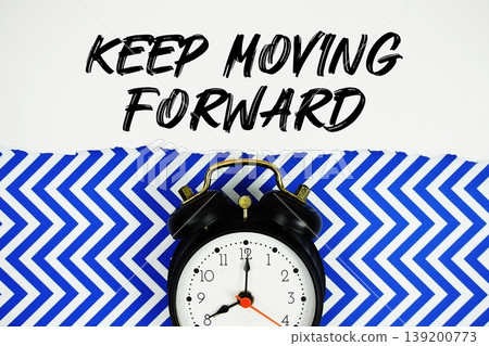 Keep Moving Forward text written on paper rip with alarm clock flat lay on blue chevron background Keep Moving Forward text written on paper rip with alarm clock flat lay on blue chevron background 139200773