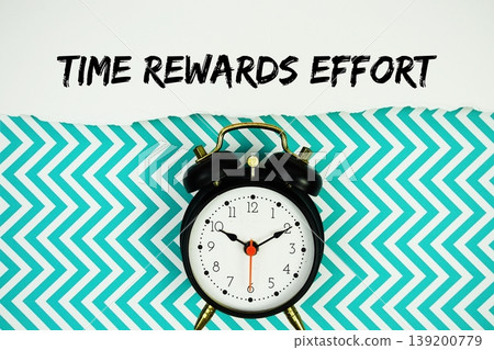 Time Rewards Effort text written on paper rip with alarm clock flat lay on turquoise chevron background Time Rewards Effort text written on paper rip with alarm clock flat lay on turquoise chevron background 139200779