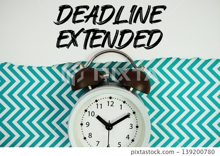 Deadline Extended text written on paper rip with alarm clock flat lay on turquoise chevron background Deadline Extended text written on paper rip with alarm clock flat lay on turquoise chevron background 139200780