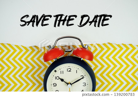 Save The Date text written on paper rip with alarm clock flat lay on yellow chevron background Save The Date text written on paper rip with alarm clock flat lay on yellow chevron background 139200783