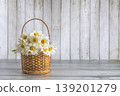 Happy birthday or mothers day greeting card template; bouquet of white daisy flowers in a wicker basket on a wooden background, copy space 139201279