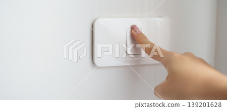 Female finger pushing for turn on light switch on white wall at home room. Woman hand turn off lighting Switch. Energy Saving, energy power control, electrical, eco environment, and lifestyle concept 139201628
