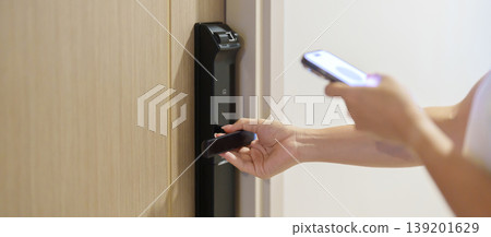 Hand using smartphone for close or Open digital door lock at home or apartment. NFC Technology, Fingerprint scan, keycard, PIN number, smartphone, electrical and contactless lifestyle concepts 139201629
