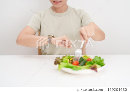 happy smiling woman with fresh organic vegetables plate and checking time. intermittent fasting, IF, nutrition control, weight loss, clean eating, Healthy food eating, Wellness, dieting and lifestyle 139201680