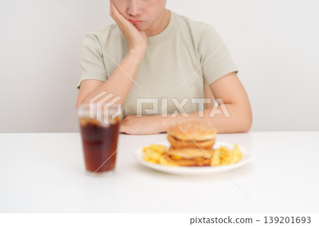 Unhappy woman disgust gesture and Bored to eat Juicy beef burger, potato chips and carbonated Soft drinks. Unhealthy, High calorie, Fast food craving, Obesity, diet, weight loss and junk food Unhappy woman disgust gesture and Bored to eat Juicy beef burger, potato chips and carbonated Soft drinks. Unhealthy, High calorie, Fast food craving, Obesity, diet, weight loss and junk food 139201693