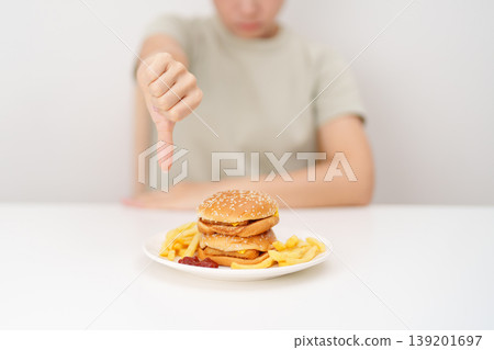 woman showing thumbs down, Rejecting and refusing with Juicy beef burger, potato chips and carbonated Soft drinks. Unhealthy, High calorie, Fast food craving, Obesity, diet, weight loss and junk food woman showing thumbs down, Rejecting and refusing with Juicy beef burger, potato chips and carbonated Soft drinks. Unhealthy, High calorie, Fast food craving, Obesity, diet, weight loss and junk food 139201697