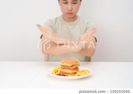 Unhappy woman showing Rejecting and refusing with Juicy beef burger, potato chips and carbonated Soft drinks. Unhealthy, High calorie, Fast food craving, Obesity, diet, weight loss and junk food 139201698