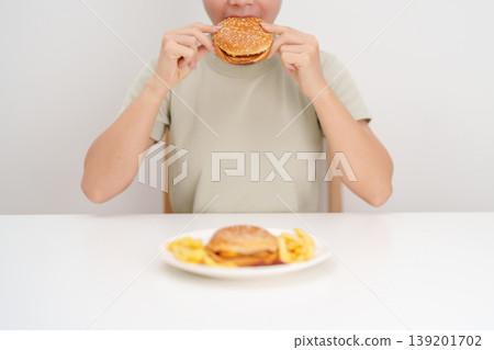 happy woman eating Juicy beef burger with melted cheddar cheese, potato chips. Unhealthy, High calorie, Fast food craving, Obesity, diet, weight loss, junk food and lifestyle 139201702