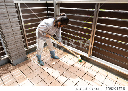 A child cleaning the balcony with a deck brush. A child cleaning the balcony with a deck brush. 139201718