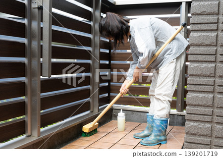 A child cleaning the balcony with a deck brush. A child cleaning the balcony with a deck brush. 139201719
