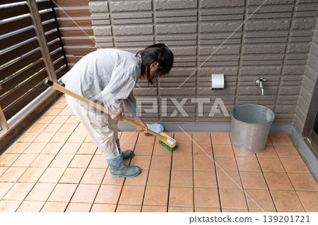 A child cleaning the balcony with a deck brush. A child cleaning the balcony with a deck brush. 139201721