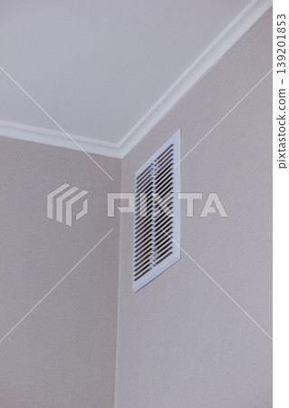 Modern white ventilation grill installed in the corner of a clean interior room wall and ceiling 139201853