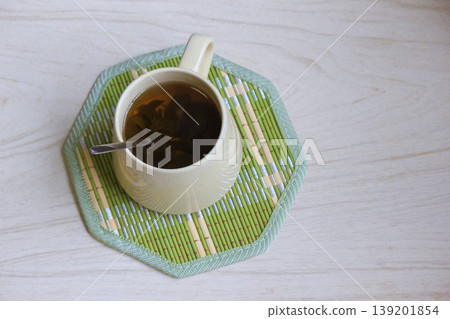 Top view of a warm cup of herbal tea steeping on a green bamboo coaster on a wooden surface Top view of a warm cup of herbal tea steeping on a green bamboo coaster on a wooden surface 139201854