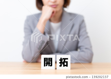 A middle-aged woman in a suit struggling with a block for development. A middle-aged woman in a suit struggling with a block for development. 139202137