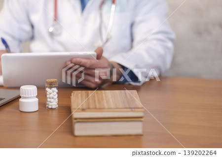 Doctor using tablet with medication on desk 139202264