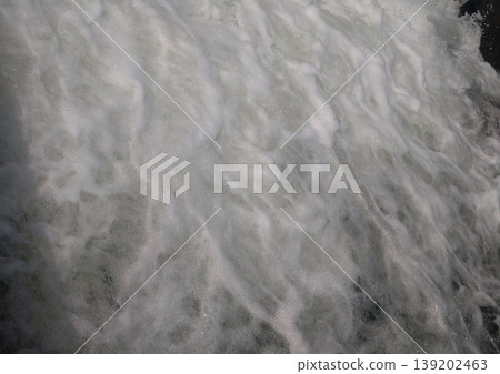 A texture of water with white waves splashing across it; a dynamic abstract background of water. 139202463