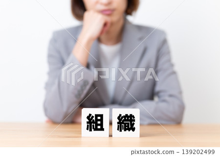 A middle-aged woman in a suit struggling with organizational stagnation. A middle-aged woman in a suit struggling with organizational stagnation. 139202499