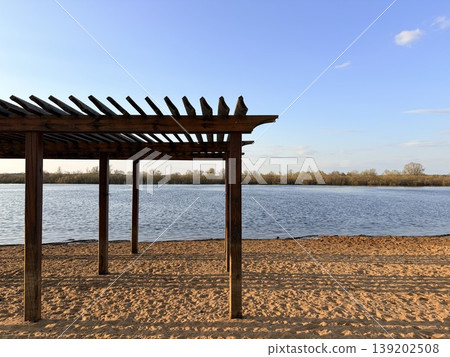 Country beach by the river, wooden canopy against the blue sky of the beach and the river. 139202508