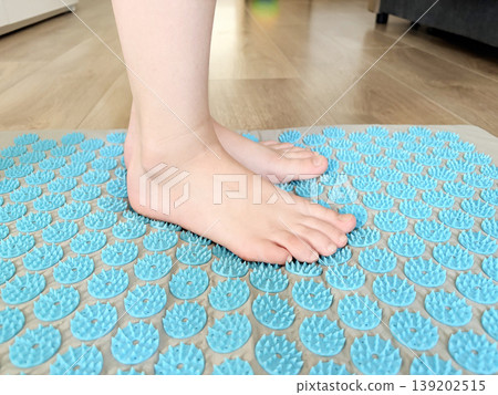 the child's feet are on a carpet with spikes 139202515