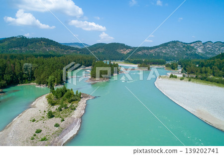 Majestic Katun River winding through dense green forests and rugged mountains on a bright summer day Majestic Katun River winding through dense green forests and rugged mountains on a bright summer day 139202741