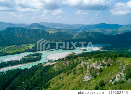 Turquoise Katun River winding through green forested Altai Mountains under a bright sky Turquoise Katun River winding through green forested Altai Mountains under a bright sky 139202743